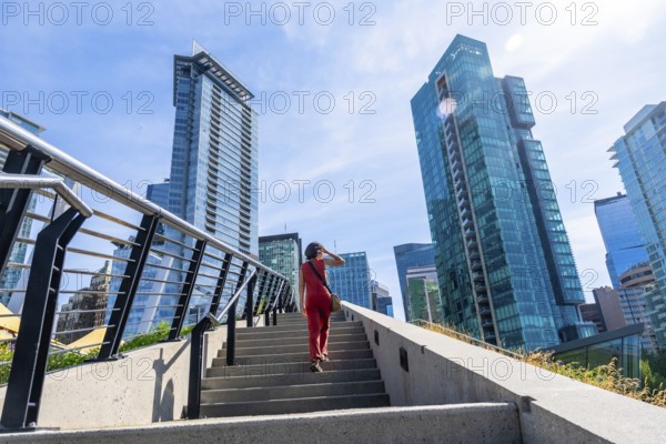 Businesswoman climbing stairs with modern skyscrapers in background in vancouver, british columbia, representing urban lifestyle, business travel, and tourism in canada