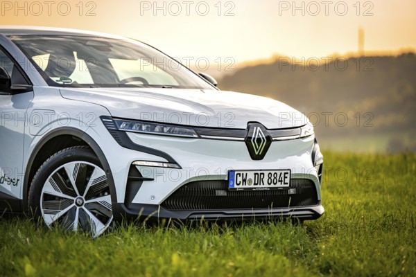 White car on a green field with a view of a sunset in a rural area, Deer e-car sharing, Renault Megane, Calw, Germany
