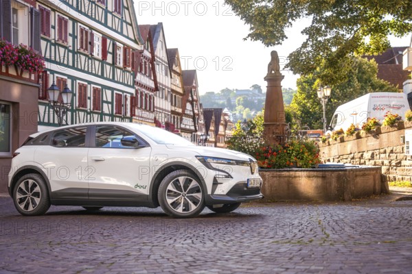 White Renault parks at a fountain in a picturesque old town, Deer e-Carsharing, Renault Megane, Calw, Germany