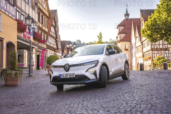 White car on a paved road in a European city center in sunshine, Deer E- car sharing, Renault Megane, Calw, Germany