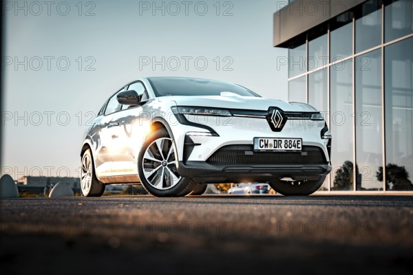 Electric car reflected in front of a modern glass building at dusk, Deer e-Carsharing, Renault Megane, Calw, Germany