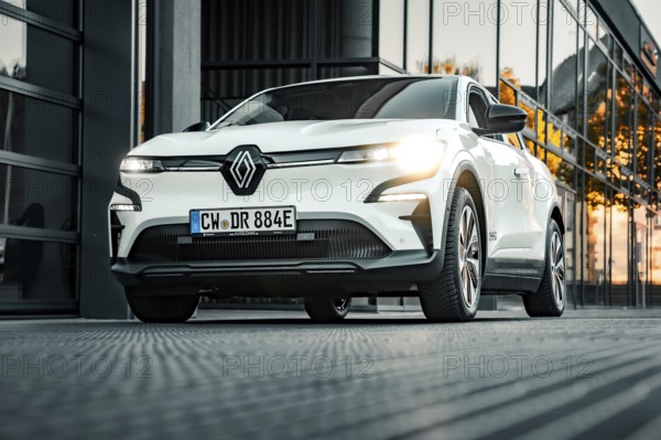 White Renault car in front of a modern glass building at sunset, Deer e-car sharing, Renault Megane, Calw, Germany