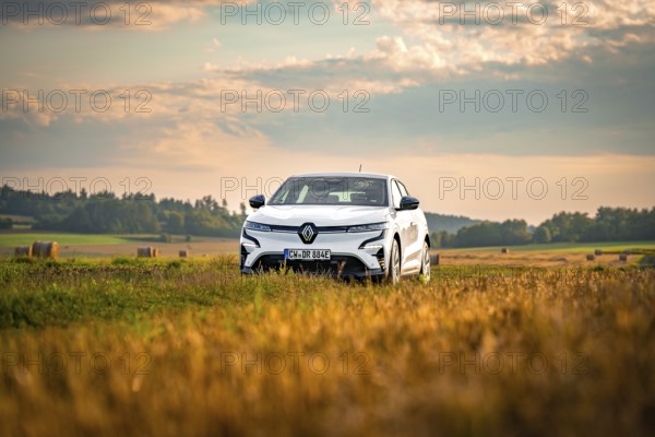 A white car drives through vast fields under a cloudy sky, Deer E-Carsharing, Renault Megane, Calw, Germany