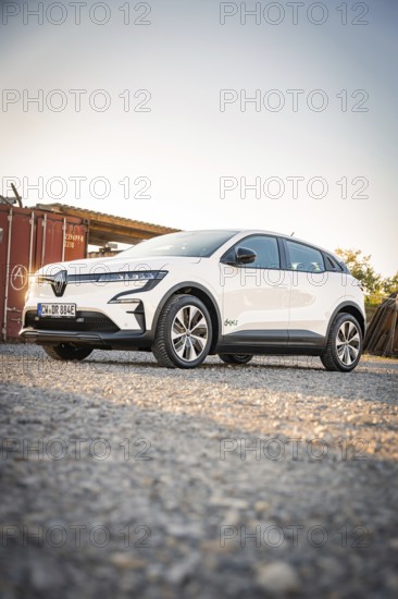 A white electric car is parked on a dirt road in the evening light in front of a container, Deer E-Carsharing, Renault Megane, Calw, Germany