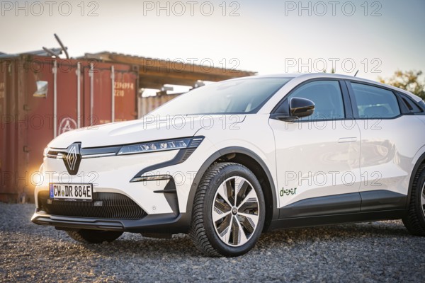 A white electric car stands on a gravel field in front of a container at dusk, Deer E-Carsharing, Renault Megane, Calw, Germany