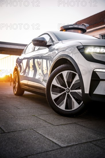 White car at sunset with reflective surfaces in front of urban architecture, Deer e-car sharing, Renault Megane, Calw, Germany