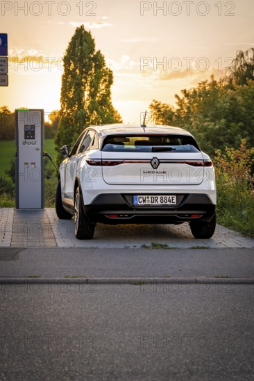 An electric car is connected to a charging station surrounded by the setting sun, Deer E-Carsharing, Renault Megane, Calw, Germany