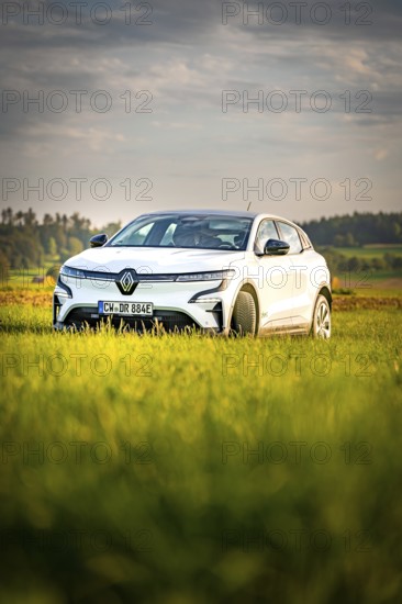 White car in a green natural setting under cloudy sky, Deer E-Carsharing, Renault Megane, Calw, Germany