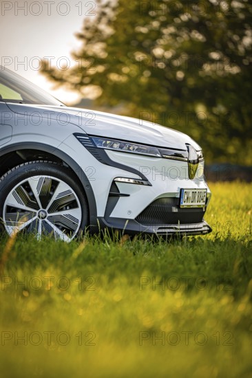 Close-up view of a white car in a meadow, focus on front tires, Deer e-Carsharing, Renault Megane, Calw, Germany