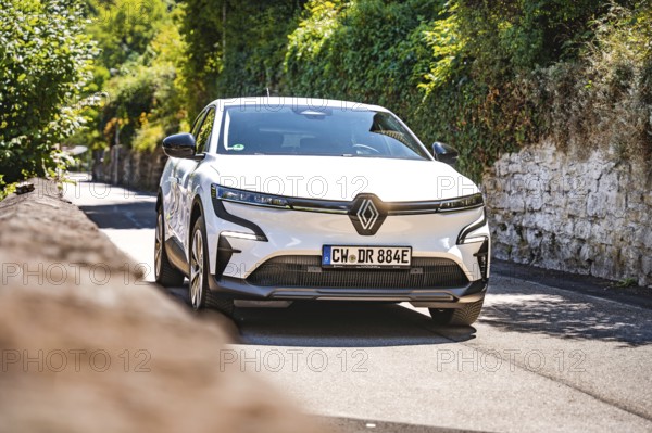White car on a country road next to a stone wall in the sun, Deer e-car sharing, Renault Megane, Calw, Germany