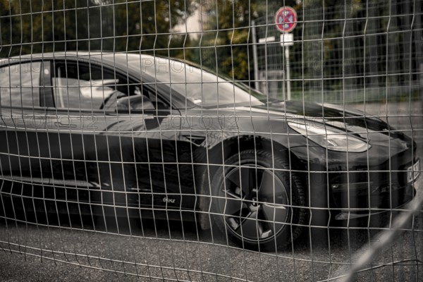 Black car behind a metal grid in an urban environment, Deer e-Carsharing, Tesla Model 3, Calw, Germany