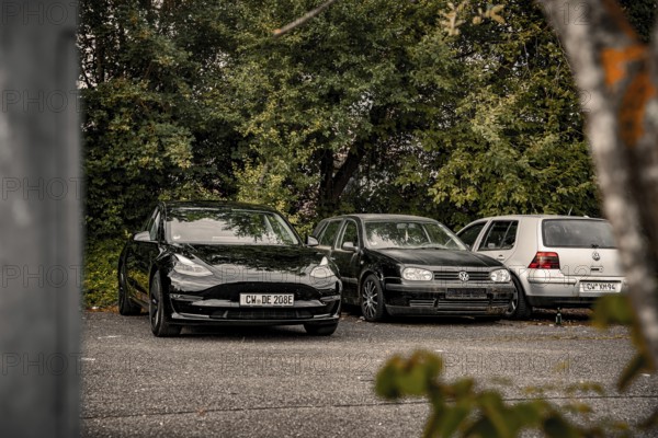 Parking lot with black cars surrounded by thick vegetation, deer e-car sharing, Tesla Model 3, Calw, Germany