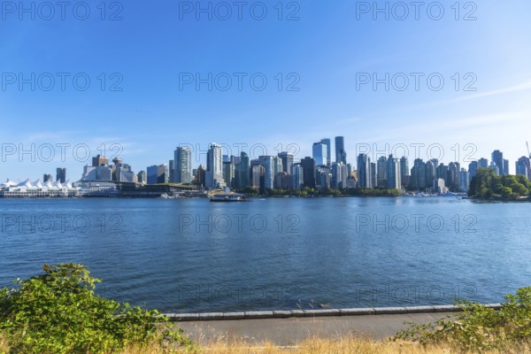 Panoramic view of vancouver's modern skyline rising above the calm pacific ocean on a sunny day, creating a vibrant urban landscape