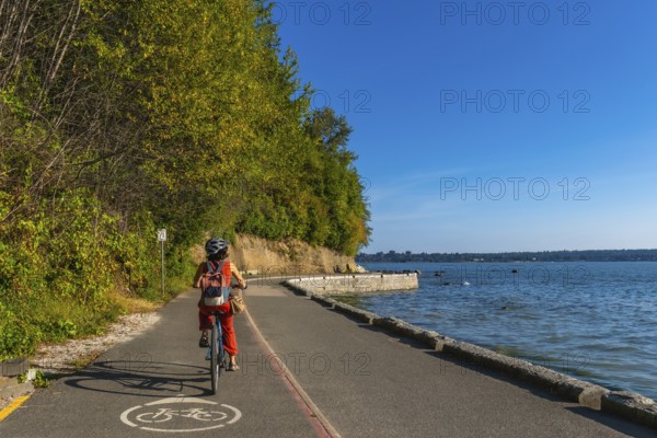 Tourist cycling through stanley park, soaking in stunning ocean views and vibrant cityscapes on a sunny summer day in vancouver, british columbia, canada