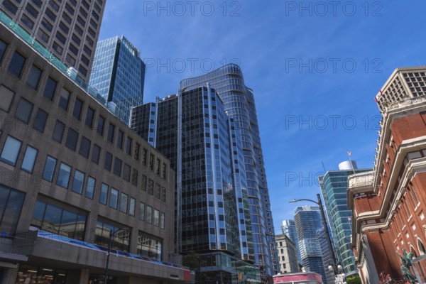 Modern glass skyscrapers and historical brick buildings stand tall against a vibrant blue sky, showcasing the architectural diversity and urban landscape of vancouver, british columbia
