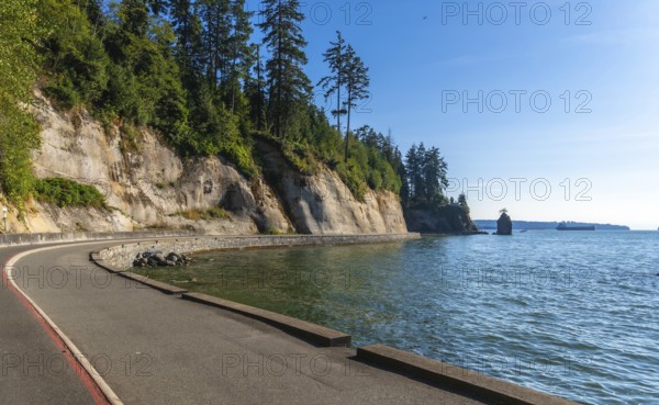 Breathtaking view of the scenic road winding along the coastline in stanley park. Vancouver. British columbia. With siwash rock in the distance. Showcasing the natural beauty of the pacific northwest