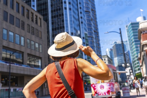 Young woman tourist holding her straw hat is admiring the skyline of vancouver downtown in british columbia, canada, during a sunny summer day