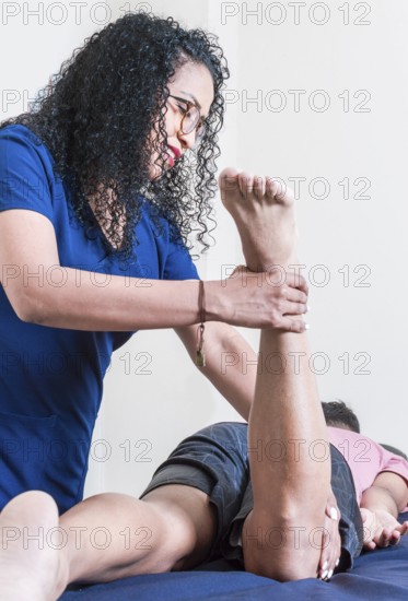 Physiotherapist with patient performing knee flexion, Smiling physiotherapist performing knee flexion physiotherapy, knee rehabilitation concept