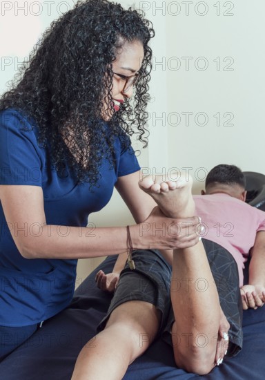 Smiling physiotherapist performing knee flexion physiotherapy, Physiotherapist with patient performing knee flexion, knee rehabilitation concept