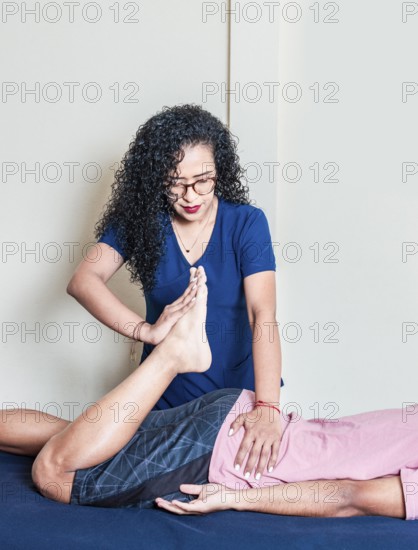 Young woman physiotherapist with lying patient. Physiotherapy rehabilitation concept, Lumbar physiotherapy treatment