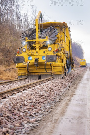 Yellow track construction machine on a railroad track in use on a construction site, tamping machine on Hermann, Hesse, Bahn, Althengstett, Calw district, Germany