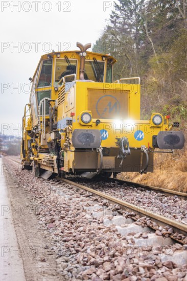 Yellow rail vehicle on tracks in an autumnal forest environment, stuffing machine on Hermann, Hesse, railway, Althengstett, Calw district, Germany