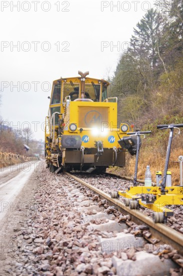 Yellow rail vehicle on tracks in foggy forest landscape, surrounded by tools, stuffing machine on Hermann, Hesse, railway, Althengstett, Calw district, Germany