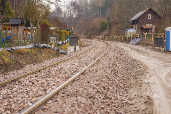 Railway tracks through quiet rural area with houses and trees in the background, stuffing machine on Hermann, Hesse, railway, Althengstett, Calw district, Germany