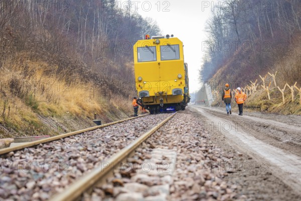 Yellow vehicle on rails with construction workers on a gravel path in the forest, stuffing machine on Hermann, Hesse, railway, Althengstett, Calw district, Germany