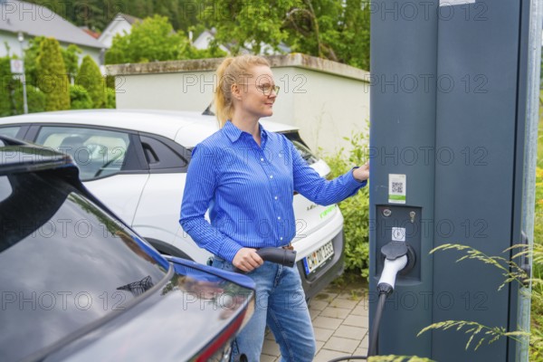 Woman uses charging station for electric cars in a municipal parking lot, Deer e-Carsharing, Calw, Germany