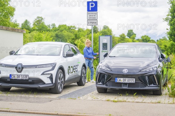 Two electric cars are parked at a charging station in a parking lot in natural surroundings, Deer E-Carsharing, Calw, Germany