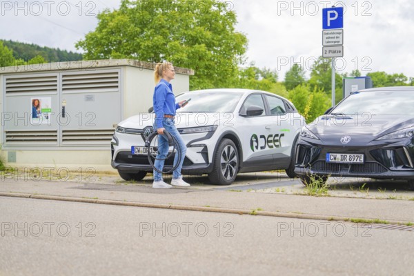 A woman prepares the charger for electric cars in a parking lot, Deer E-Carsharing, Calw, Germany