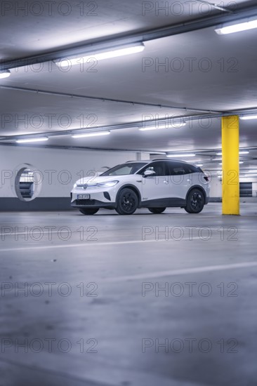 White car in empty underground garage with yellow pillar and neon light atmosphere, deer e-car sharing, VW ID4, Calw, Germany