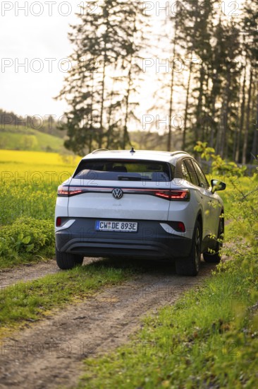 SUV traveling on a rural path surrounded by green fields, deer e-car sharing, VW ID4, Calw, Germany