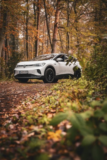 SUV in an autumn-colored forest on a narrow path, Deer E-Carsharing, VW ID4, Calw, Germany