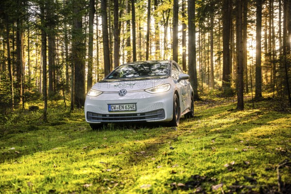 A car is parked in a sun-drenched forest, part of a car sharing service, Deer E-Carsharing, VW ID3, Calw, Germany