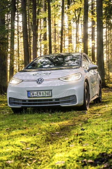 A car on a forest path, illuminated by sunlight, license plate CW EN 634E, Deer E-Carsharing, VW ID3, Calw, Germany