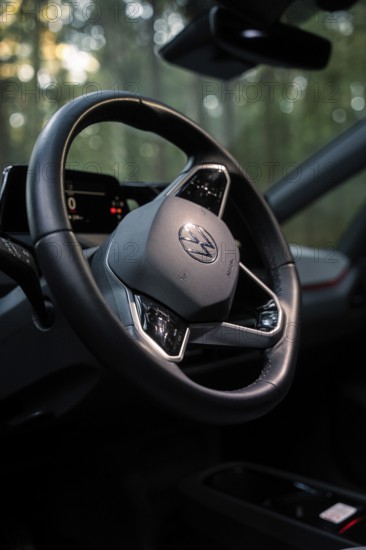 Close-up of a steering wheel in the interior of a car surrounded by a wooded background, Deer E-Carsharing, VW ID3, Calw, Germany