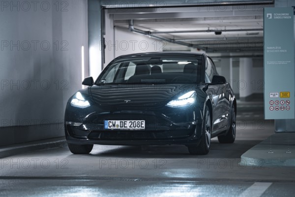 Black car drives into a modern, well-lit garage with cool atmosphere, Deer E-Carsharing, Tesla Model 3, Calw, Germany