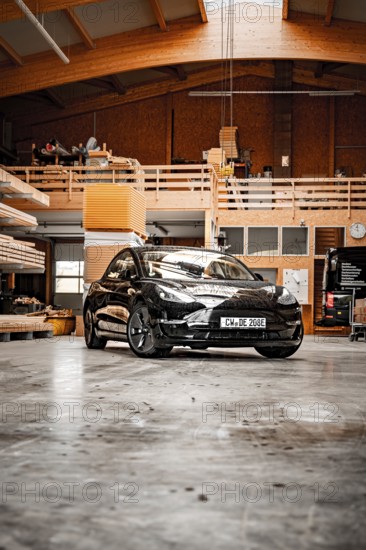 Black car parked in a wood-panelled workshop with modern architectural design, Deer e-car sharing, Tesla Model 3, Calw, Germany