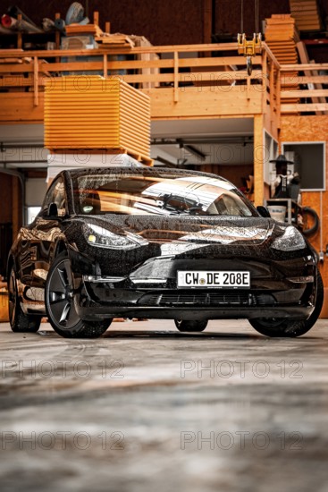 Black Tesla in a workshop environment with industrial flair, Deer e-Carsharing, Tesla Model 3, Calw, Germany