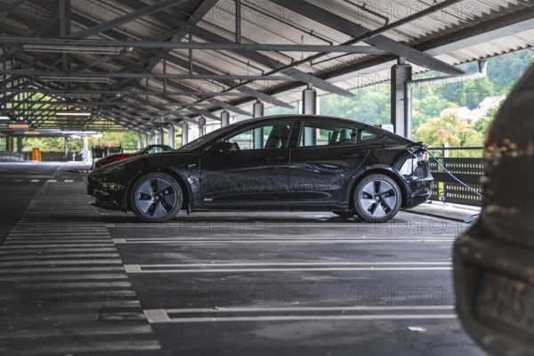 Black car in a covered parking lot with a view of nature, Deer e- car sharing, Tesla Model 3, Calw, Germany