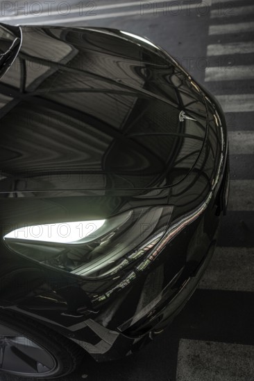 Close-up of a black car with glowing headlights and reflections, Deer E- car sharing, Tesla Model 3, Calw, Germany