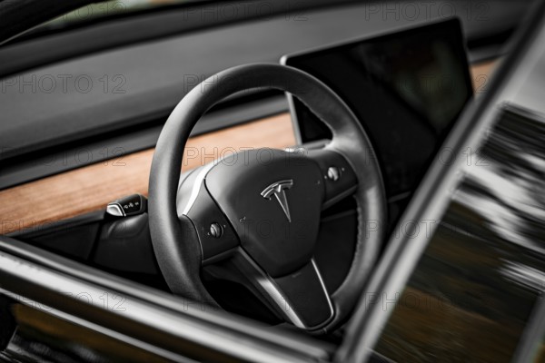 Close-up of a black steering wheel with wood paneling in modern car interior, Deer e-car sharing, Tesla Model 3, Calw, Germany