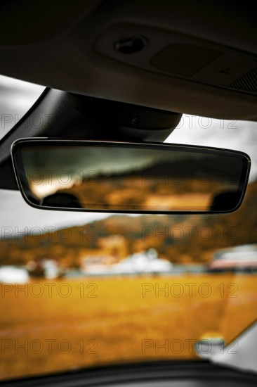 Rearview mirror in car with blurred view of landscape and buildings in background, Deer E-Carsharing, Tesla Model 3, Calw, Germany