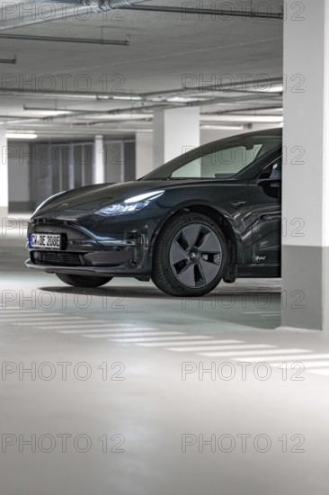 Black Tesla in parking garage, partly hidden by pillar, illuminated, Deer E-Carsharing, Tesla Model 3, Calw, Germany