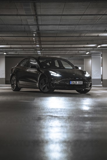Black car in a parking garage with reflecting lights on the ground, Deer E-Carsharing, Tesla Model 3, Calw, Germany