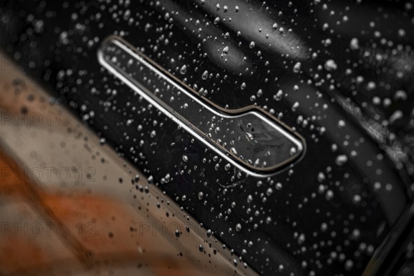 Close-up of a black car with water droplets on the surface showing shiny details, Deer E- car sharing, Tesla Model 3, Calw, Germany