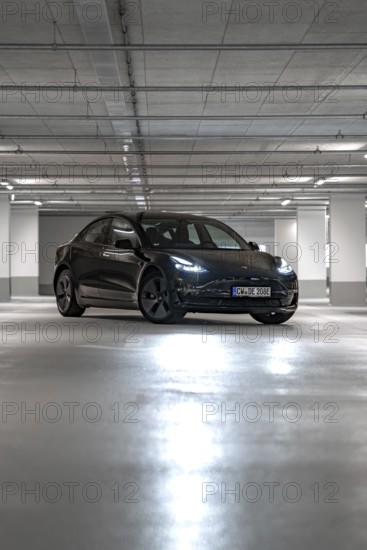 Black Tesla centrally positioned in empty, well-lit parking garage, Deer e-Carsharing, Tesla Model 3, Calw, Germany