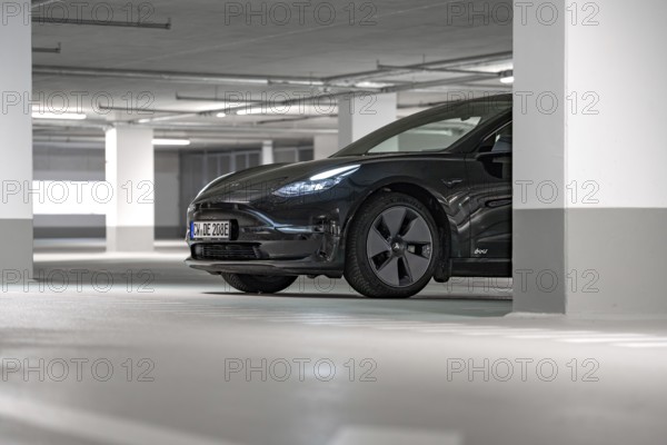 Black Tesla partially visible in a brightly lit parking garage, Deer e-Carsharing, Tesla Model 3, Calw, Germany